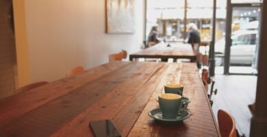 two gray ceramic mugs on brown wooden dining table